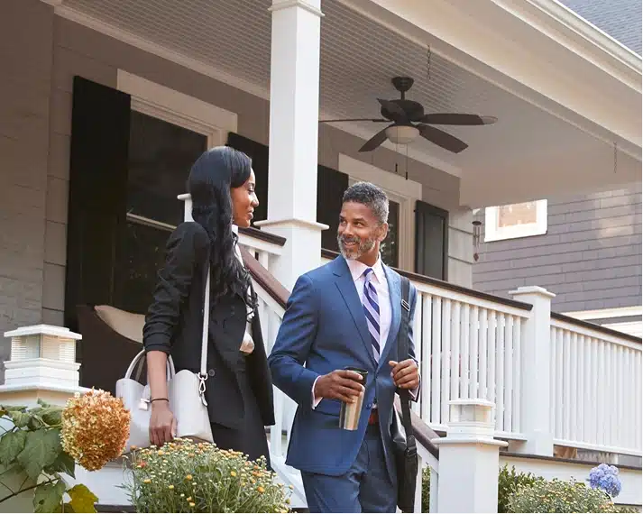 A man and woman dressed professionally walking out of the house
